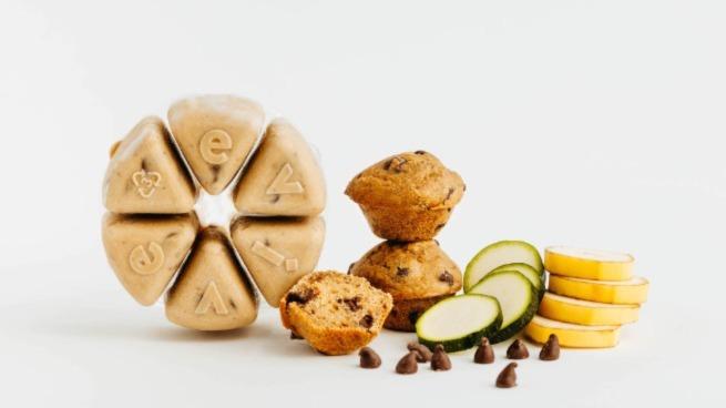 Banana-Choco frozen muffin mix wheel beside baked muffins and raw ingredients